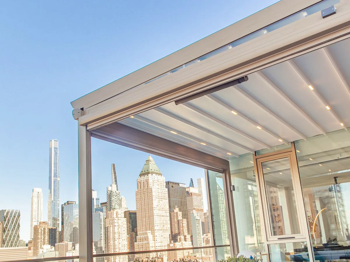 Retractable fabric roof closed over a city roof terrace, tall towers beyond the glazed flank — photograph