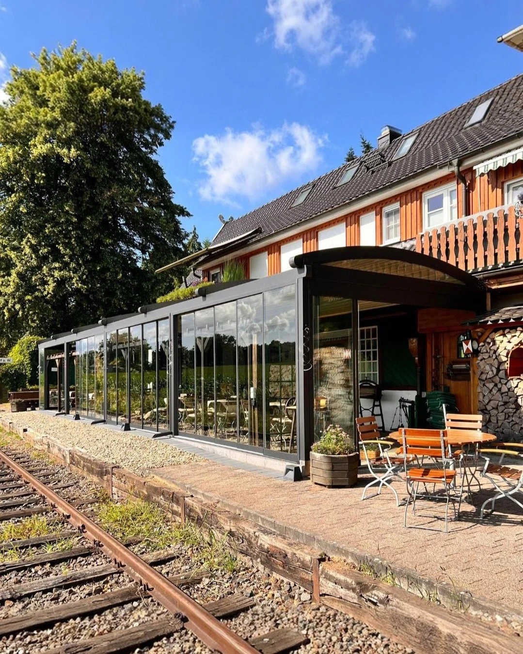 A long fabric-roof terrace with glazed sides beside a railway platform, seen from outside.