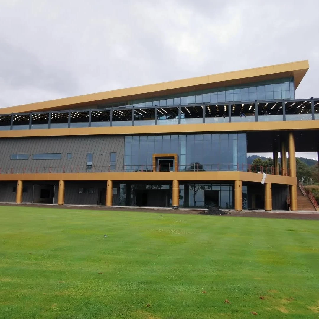 A broad exterior view of a building with a long dark fabric canopy sheltering its upper terrace.