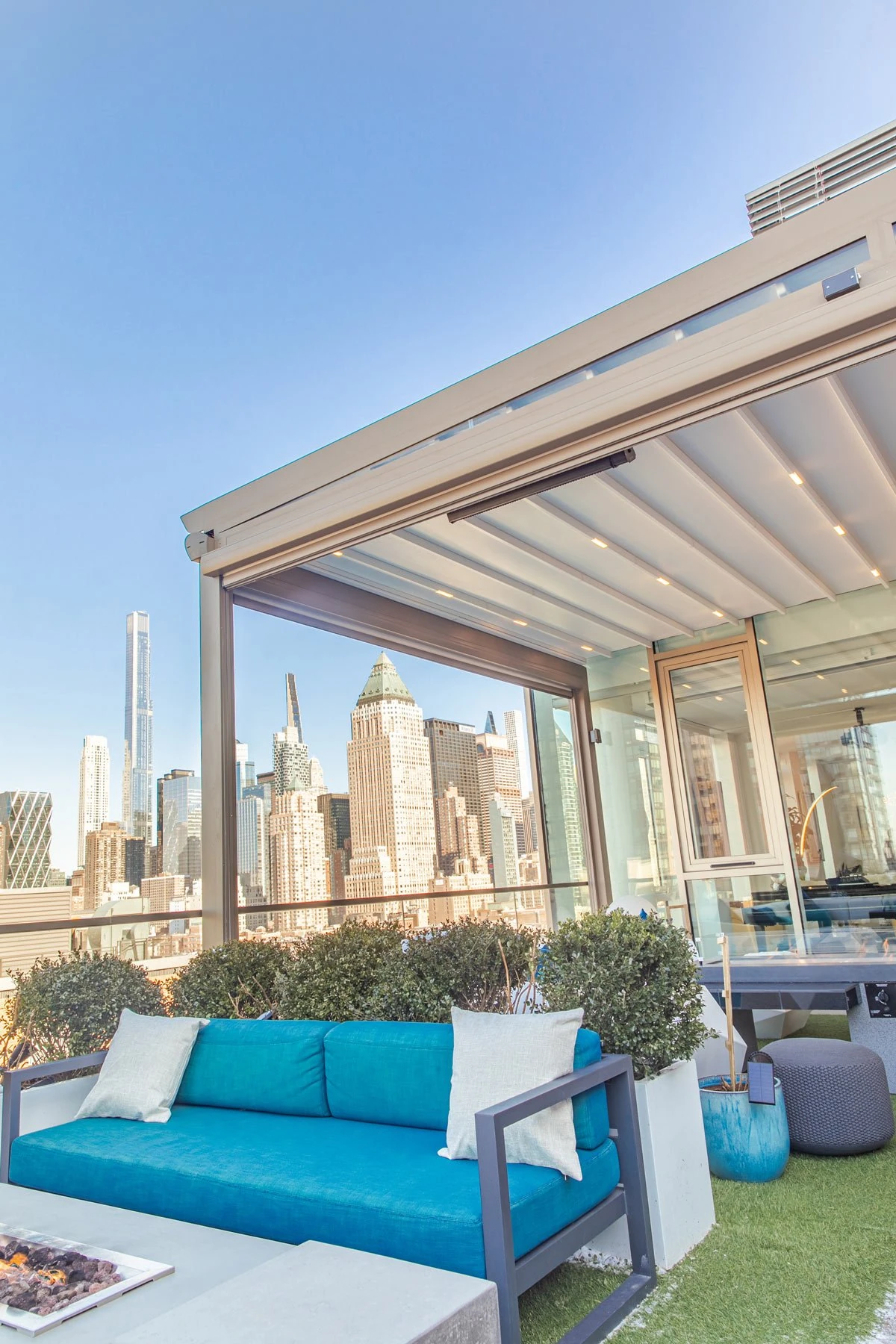 A closed fabric roof above a glazed roof terrace, with a city skyline beyond the open side.